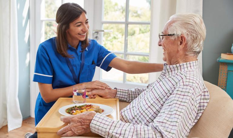 Nurse serving dinner to a senior man