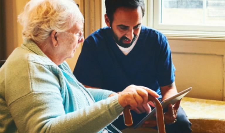 Male carer and older woman with a hand held device