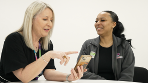 This is a picture of two women sitting at a table looking at a mobile phone