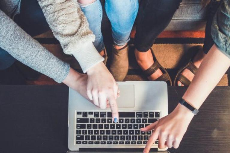 A group of people watching and pointing at a laptop screen