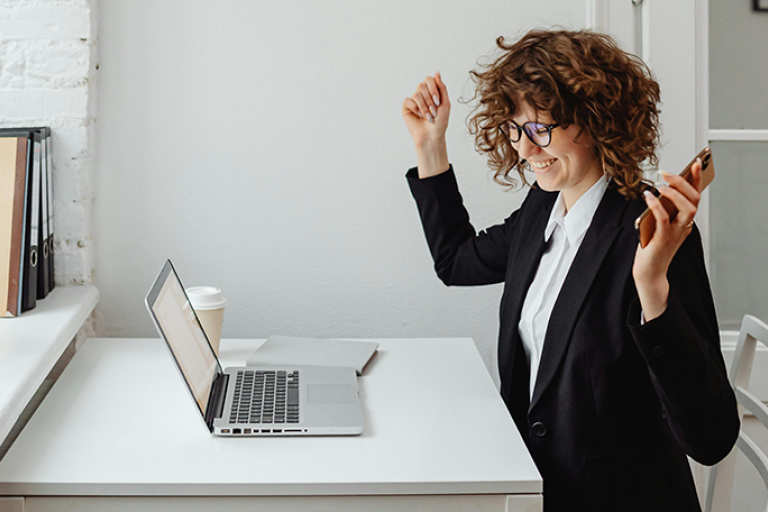 A woman celebrating on her laptop